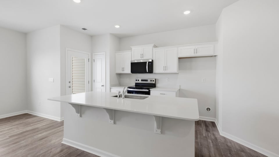 Kitchen and island with quartz countertops and stainless steel appliances.