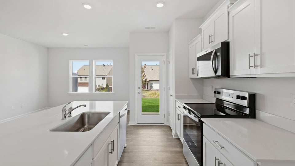 Kitchen and island with quartz countertops and stainless steel appliances.