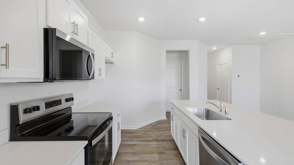 Kitchen and island with quartz countertops and stainless steel appliances.