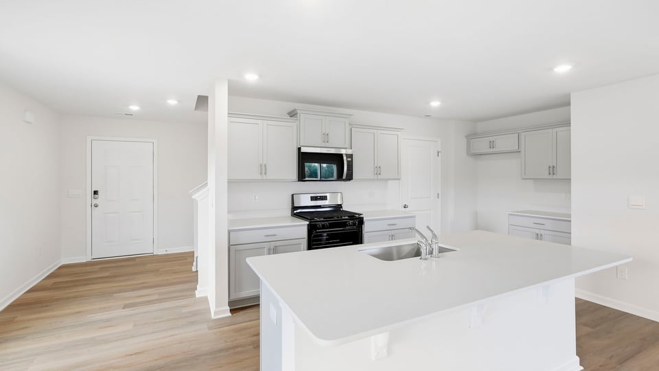 Kitchen and island with quartz countertops and stainless steel appliances.