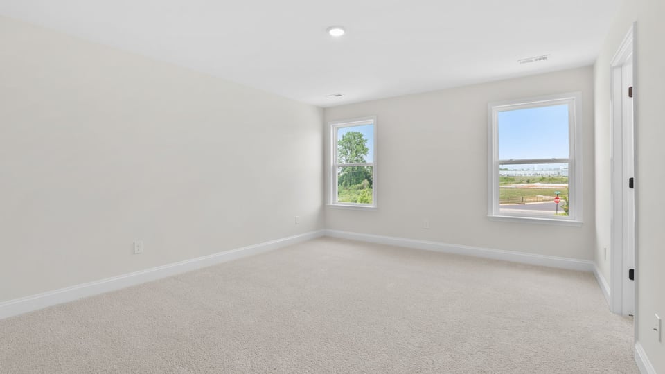 Primary bedroom with carpet and window.