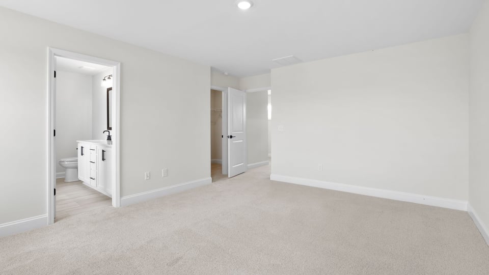 Primary bedroom with carpet and window.