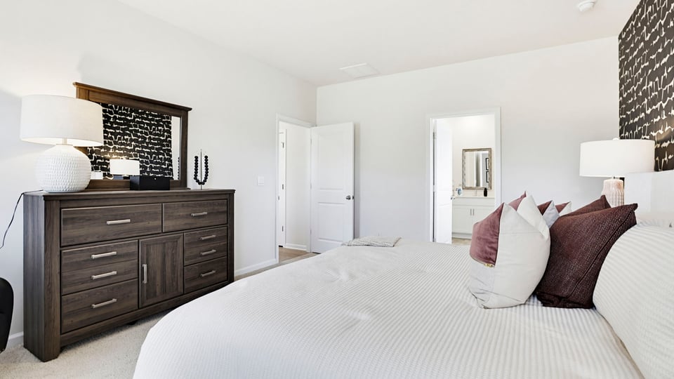 Primary bedroom with carpet and windows.