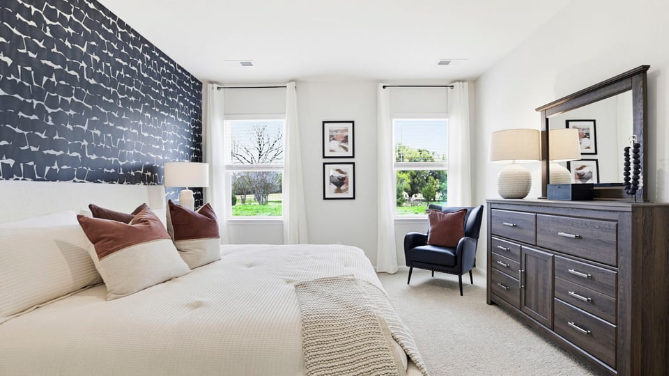 Primary bedroom with carpet and windows.