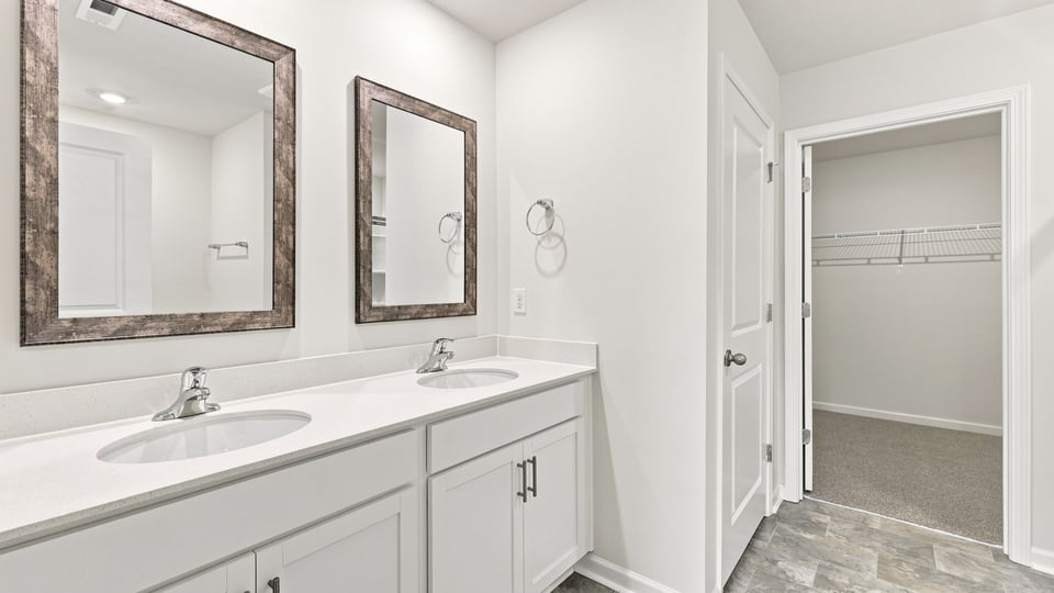 Bathroom with double vanity sink and walk in closet.