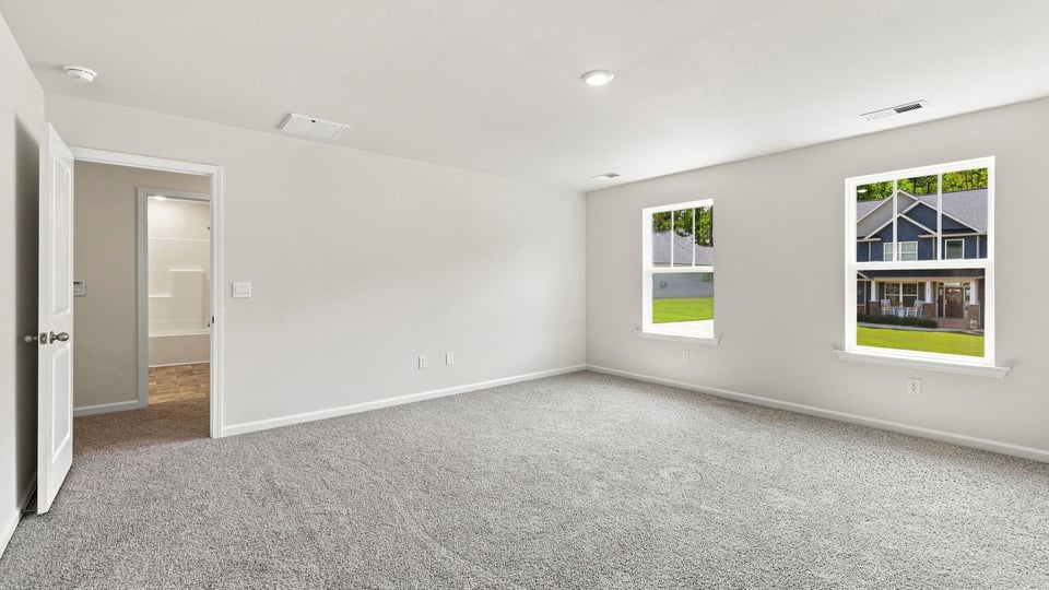 Primary bedroom with carpet and windows.