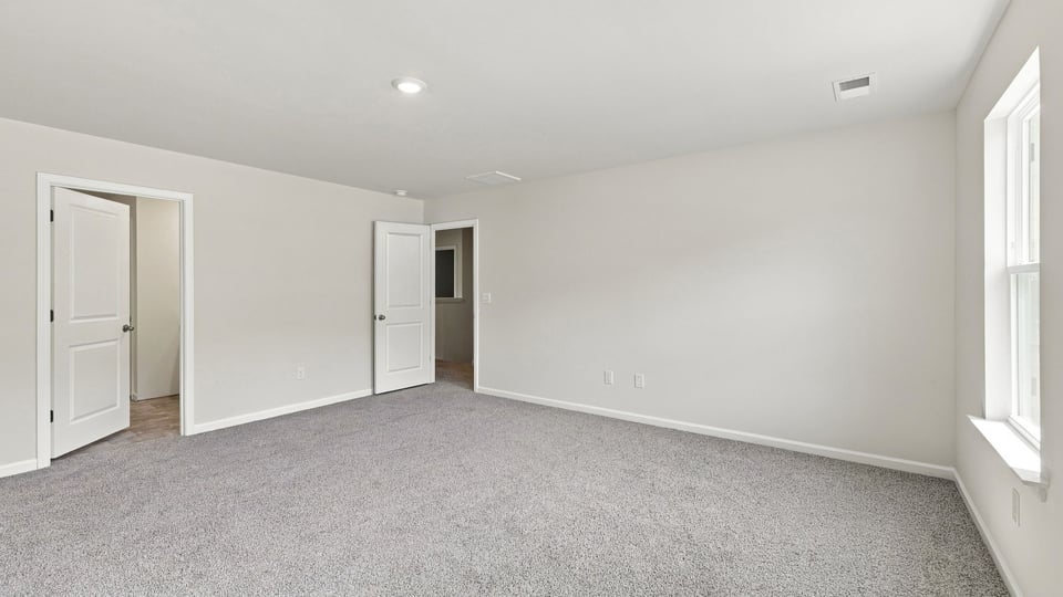 Primary bedroom with carpet and windows.