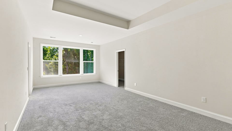 Primary bedroom with carpet and windows.