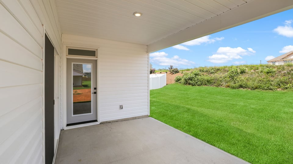 Large backyard of home with covered patio.