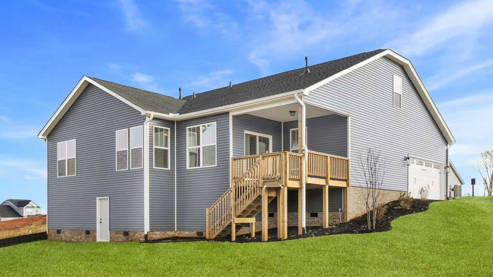 Back exterior with covered deck and large backyard.