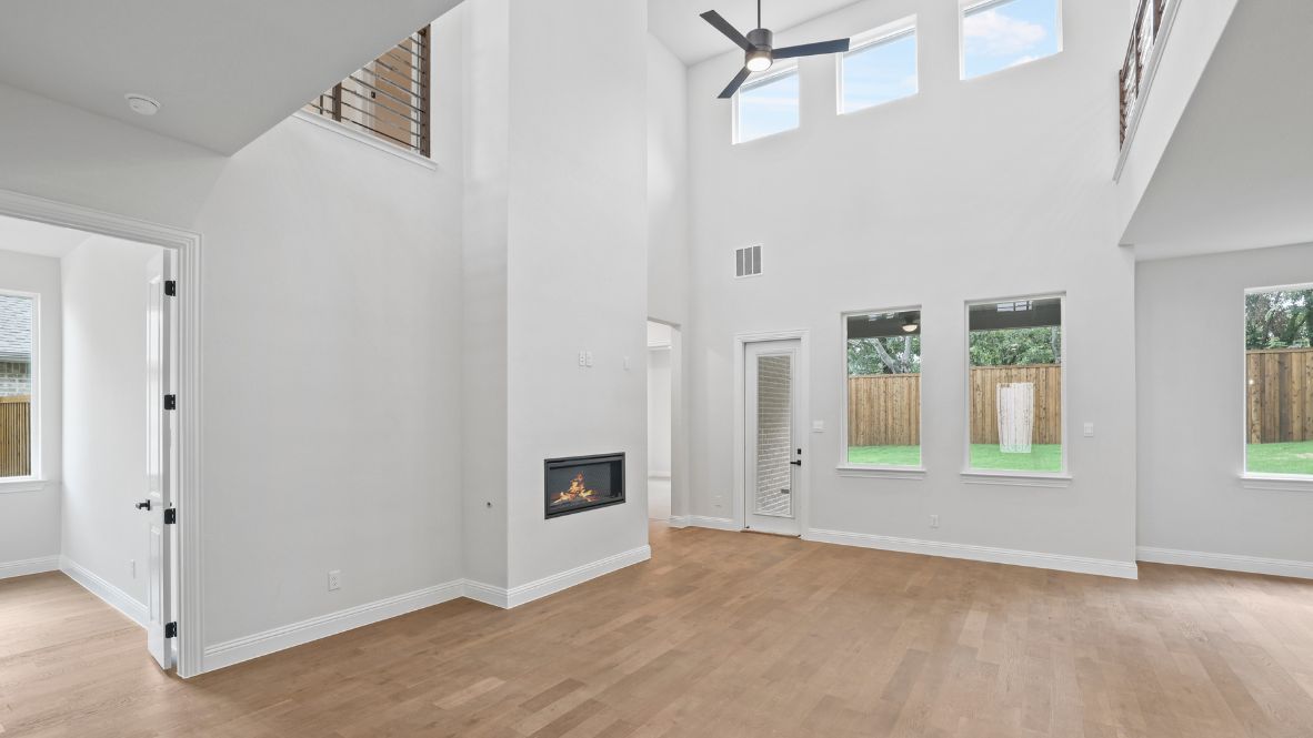 Spacious living room with brown flooring, white walls and windows