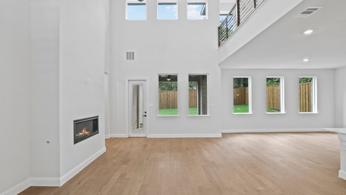 Spacious living room with brown flooring, white walls and windows