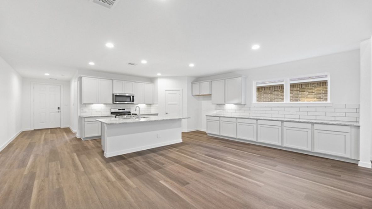 The main living space is open-concept, blending the living room, dining area, and kitchen into one harmonious area ideal for entertaining or relaxing with family. Large windows fill the space with natural light, highlighting the luxurious finishes and modern flooring. The kitchen is a chef’s dream, featuring an oversized center island, ample countertop space, sleek cabinetry, and state-of-the-art appliances. Adjacent to the kitchen is a spacious walk-in pantry, ensuring you’ll never run out of storage.