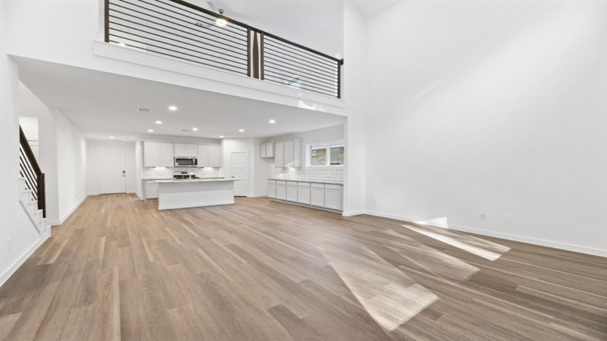 The main living space is open-concept, blending the living room, dining area, and kitchen into one harmonious area ideal for entertaining or relaxing with family. Large windows fill the space with natural light, highlighting the luxurious finishes and modern flooring. The kitchen is a chef’s dream, featuring an oversized center island, ample countertop space, sleek cabinetry, and state-of-the-art appliances. Adjacent to the kitchen is a spacious walk-in pantry, ensuring you’ll never run out of storage.