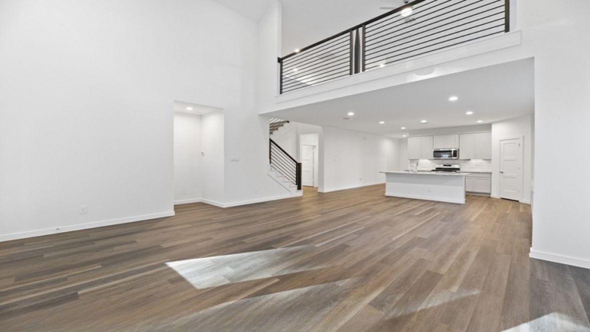 The main living space is open-concept, blending the living room, dining area, and kitchen into one harmonious area ideal for entertaining or relaxing with family. Large windows fill the space with natural light, highlighting the luxurious finishes and modern flooring. The kitchen is a chef’s dream, featuring an oversized center island, ample countertop space, sleek cabinetry, and state-of-the-art appliances. Adjacent to the kitchen is a spacious walk-in pantry, ensuring you’ll never run out of storage.