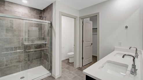 primary bathroom with full tile surround walk in shower with double vanity quartz countertops