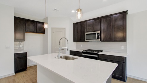 gourmet kitchen with shaker style cabinetry quartz countertops stainless steel appliances and pendants over the island
