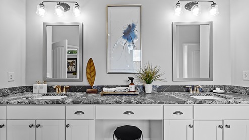ashley model home primary suite bathroom with large dual vanity with sitting spot