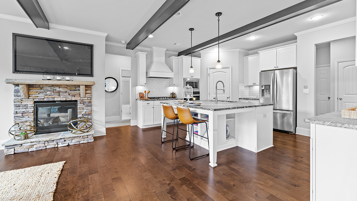 ashley model home kitchen open to living room with stacked stone fireplace