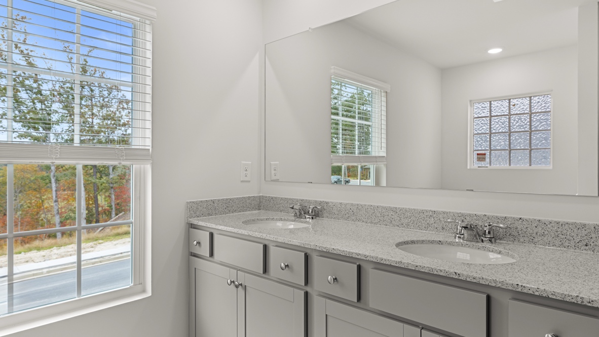 Interior primary bathroom with double sink and window