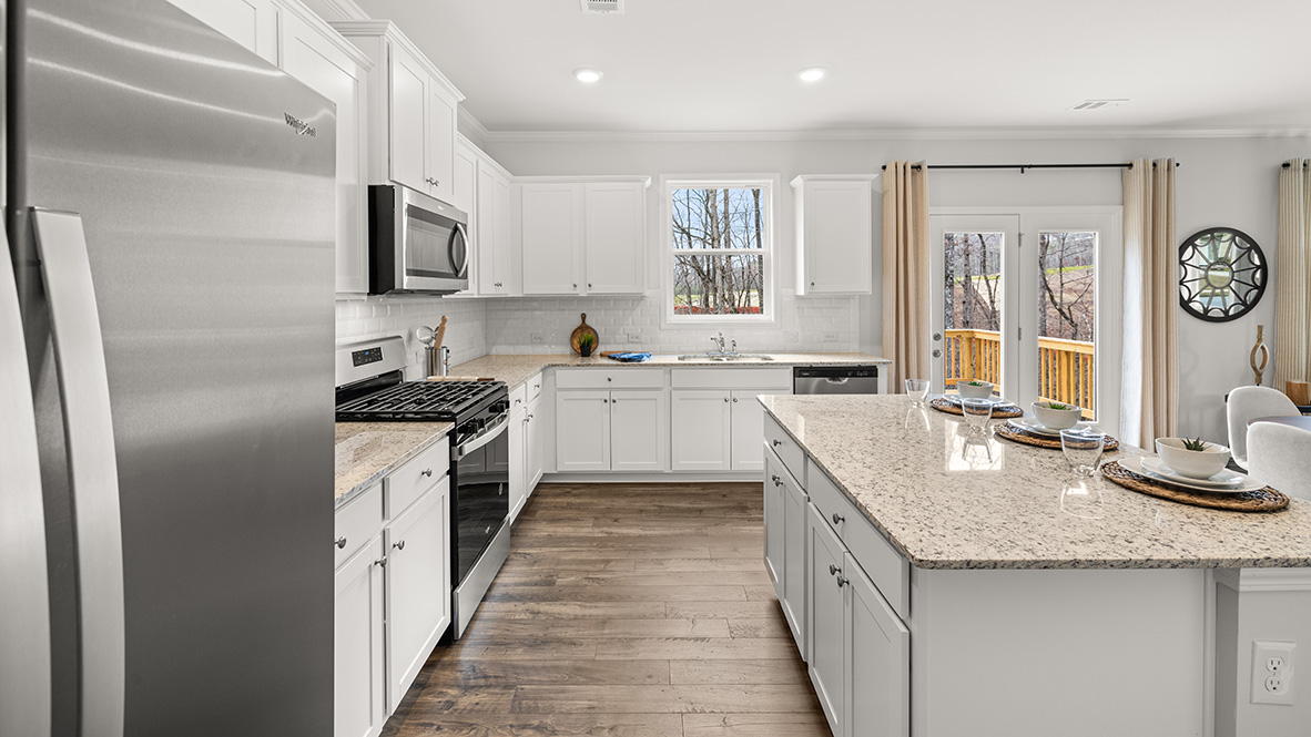 Kitchen island at center of Hanover Plan in Lost Creek showing New Strong Hard Surface Countertops and connected dining area