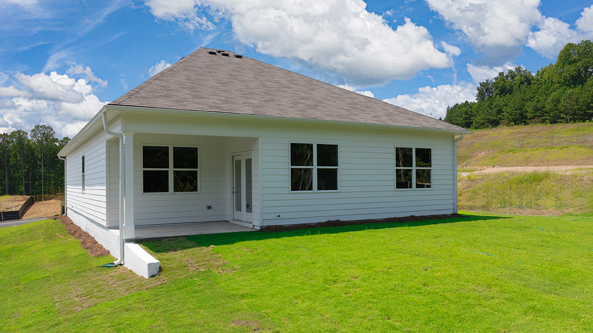 Covered rear patio with outdoor seating area, lawn space, and sliding glass door access