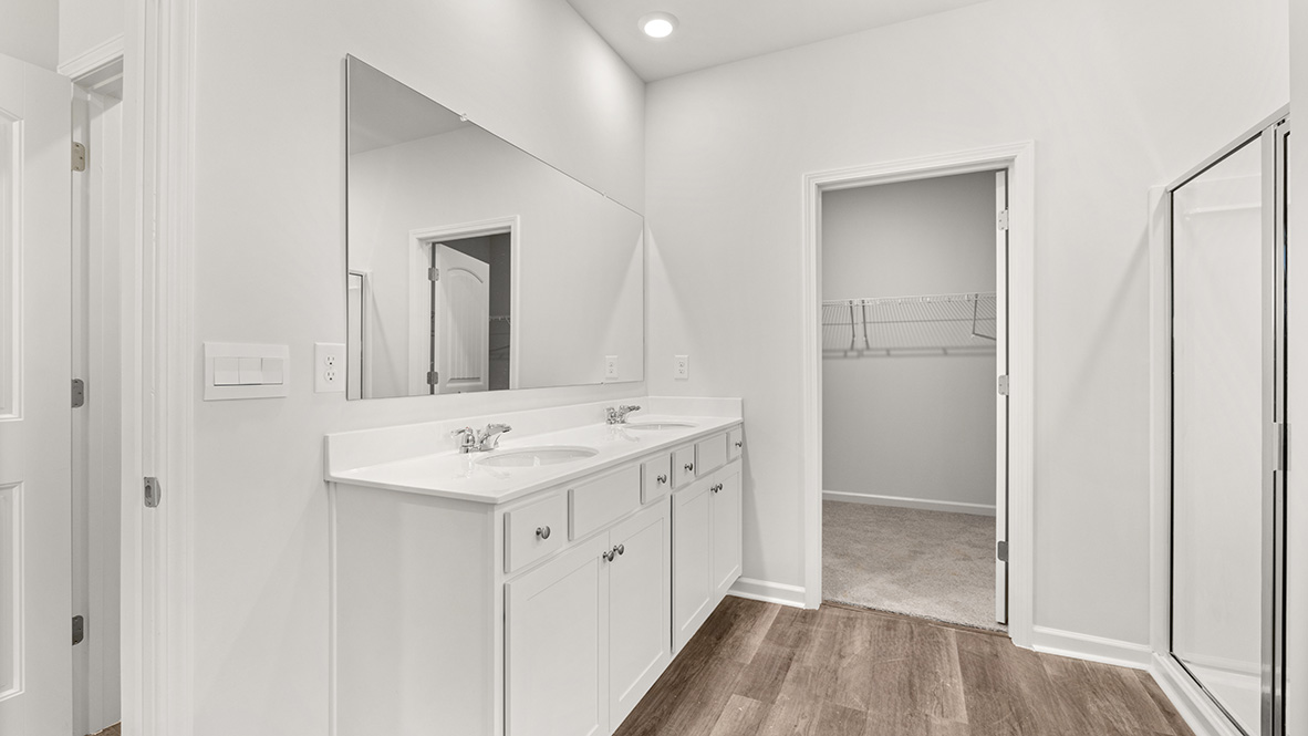 Interior primary bathroom with double sink, walk in closet and shower
