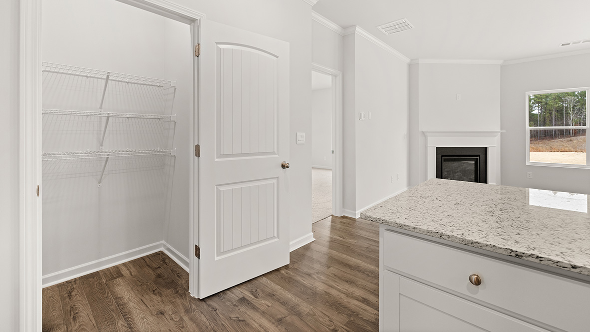 Side angle of the kitchen showing granite countertops, stainless steel dishwasher, and a deep sink under a wide window.
