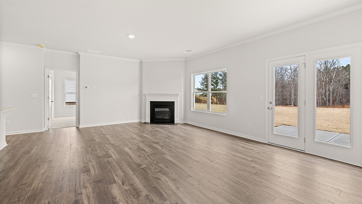 Spacious living area with wood-style flooring, large window, and open layout leading to adjacent rooms.