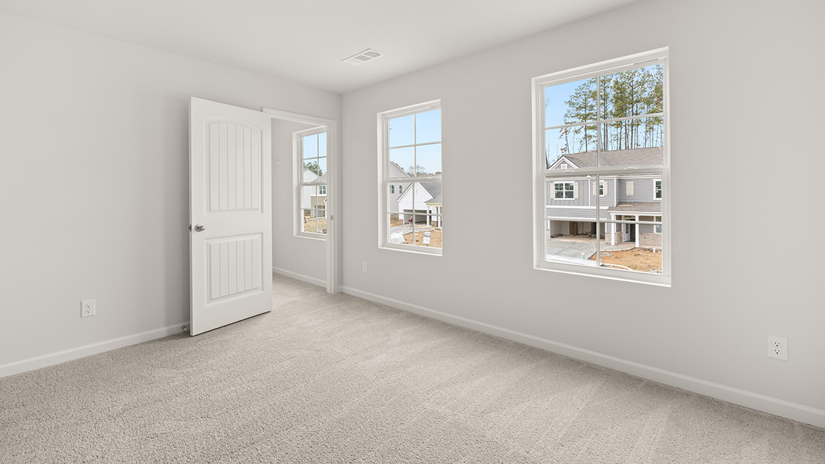 Bedroom with two windows and two doors leading to hallway and landing.