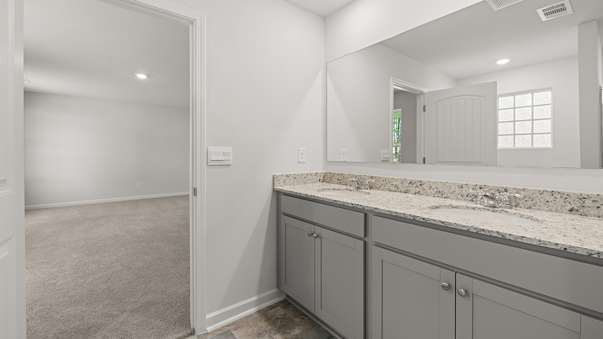 Interior primary bathroom with double sink open to bedroom