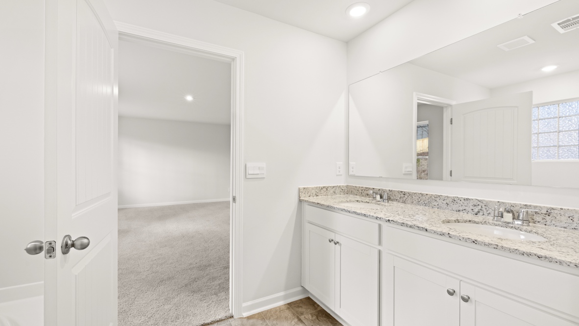 Interior primary bathroom with double sink open to bedroom