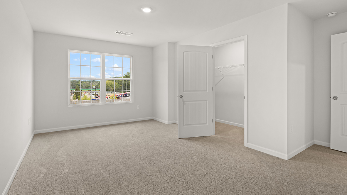 Interior primary bedroom with large window and closet