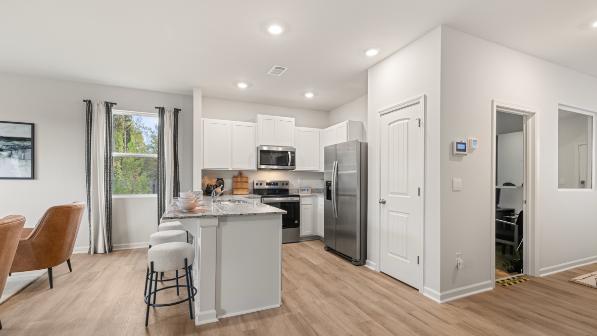 Interior kitchen with white cabinets open to living area