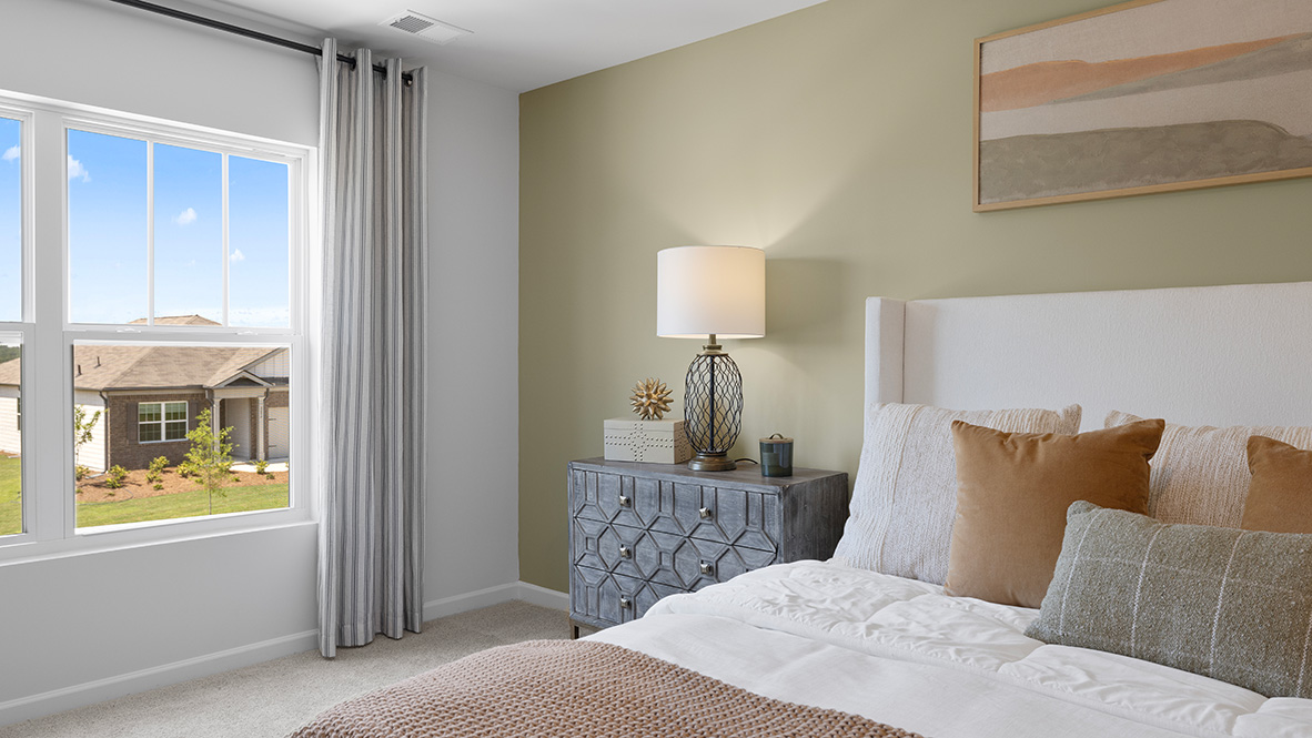 Interior primary bedroom with accent wall and large window