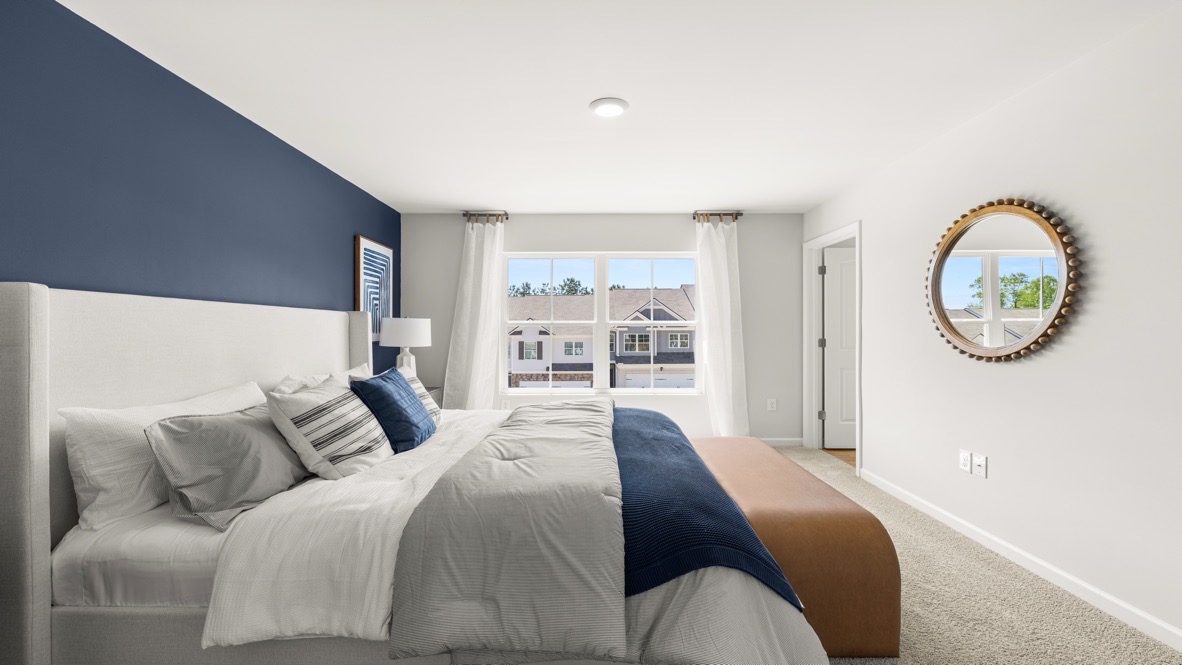 Interior primary bedroom with dark blue accent wall and large window