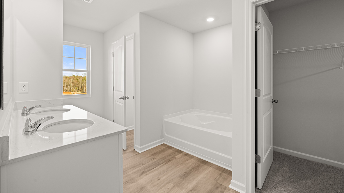 spacious bathroom with dual sinks and white cabinetry