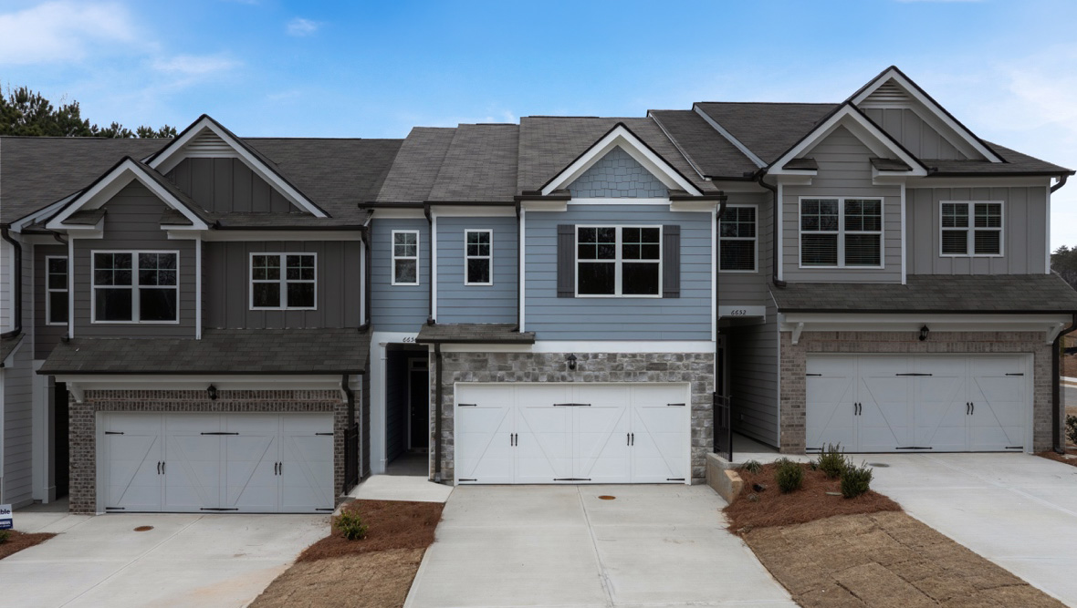 front exterior view of white and grey townhomes with brick accents