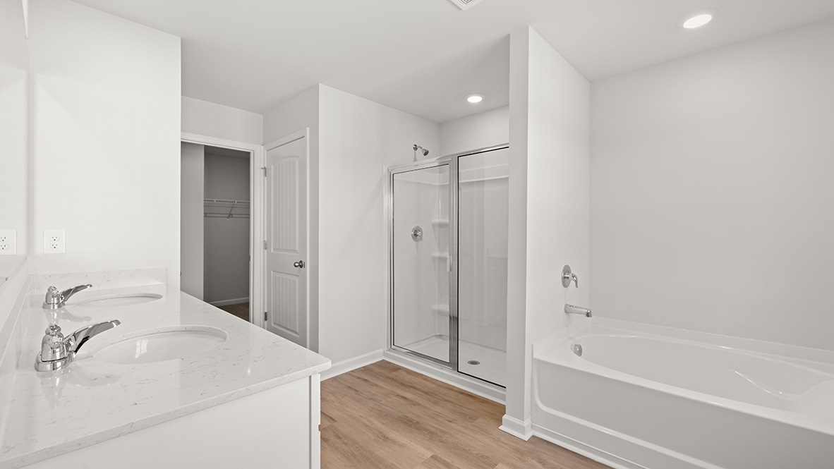 Interior primary bathroom with double sink, shower and bath tub