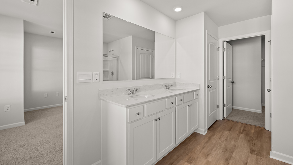 Interior primary bathroom with double sink and walk-in closet