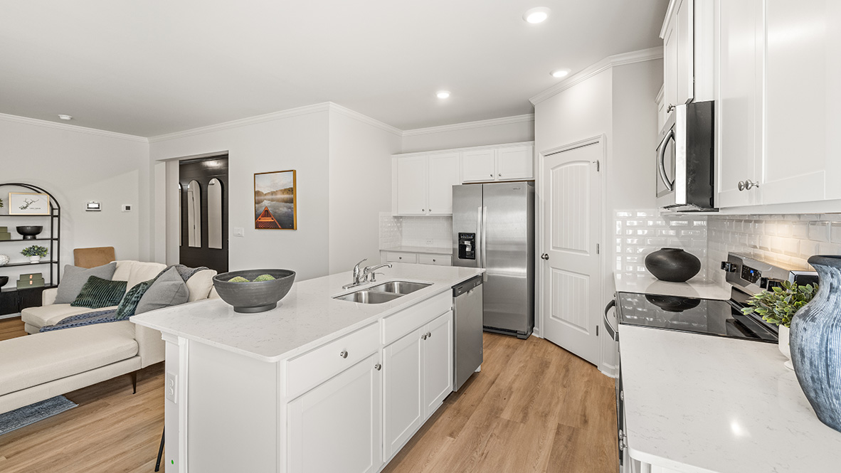 spacious modern white kitchen with tile backsplash, stainless steel appliances and white cabinets