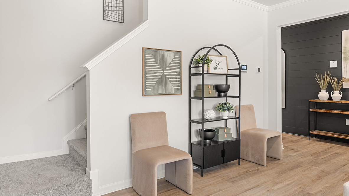 decorated side of the hallway wall with a black bookshelf and 2 light beige suede chairs