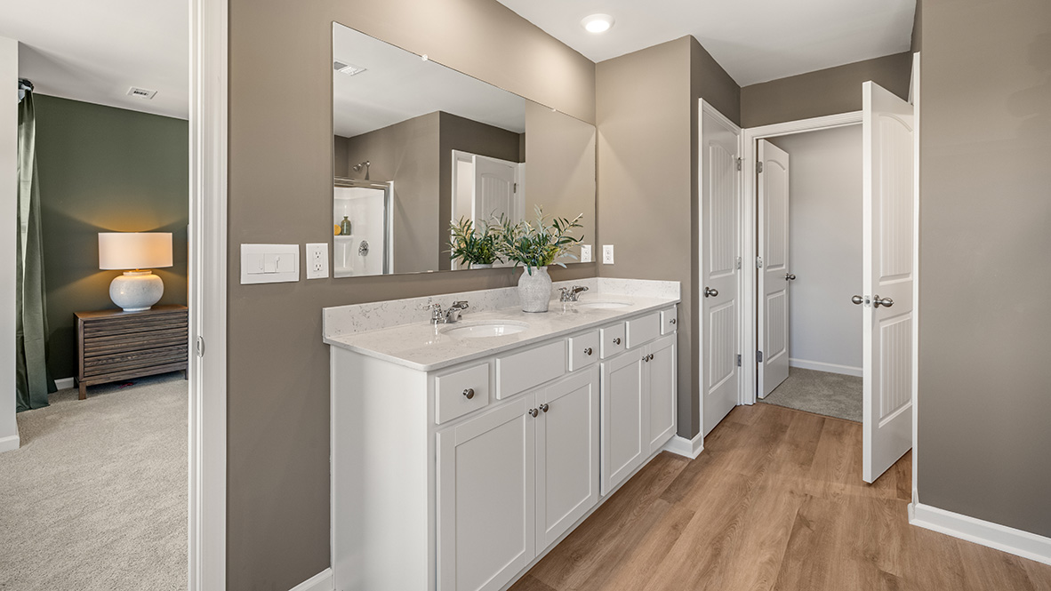 primary bathroom featuring dual isnks, white cabinetry and a large mirror