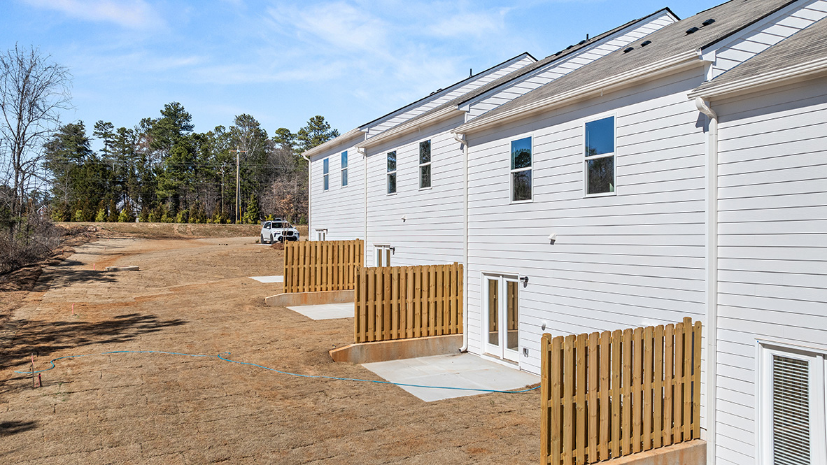 rear exterior view of home featuring privacy fence on the left and grass