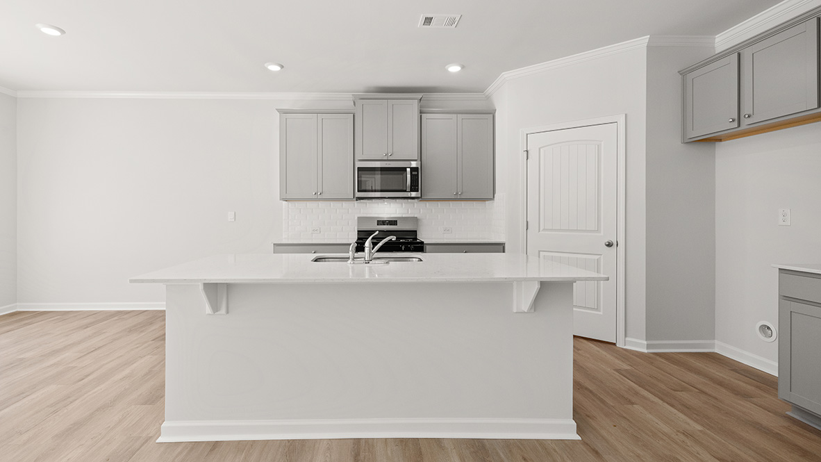 The kitchen has an island with a sink, granite countertops, grey shaker-style cabinets, a subway tile backsplash, and stainless steel appliances.