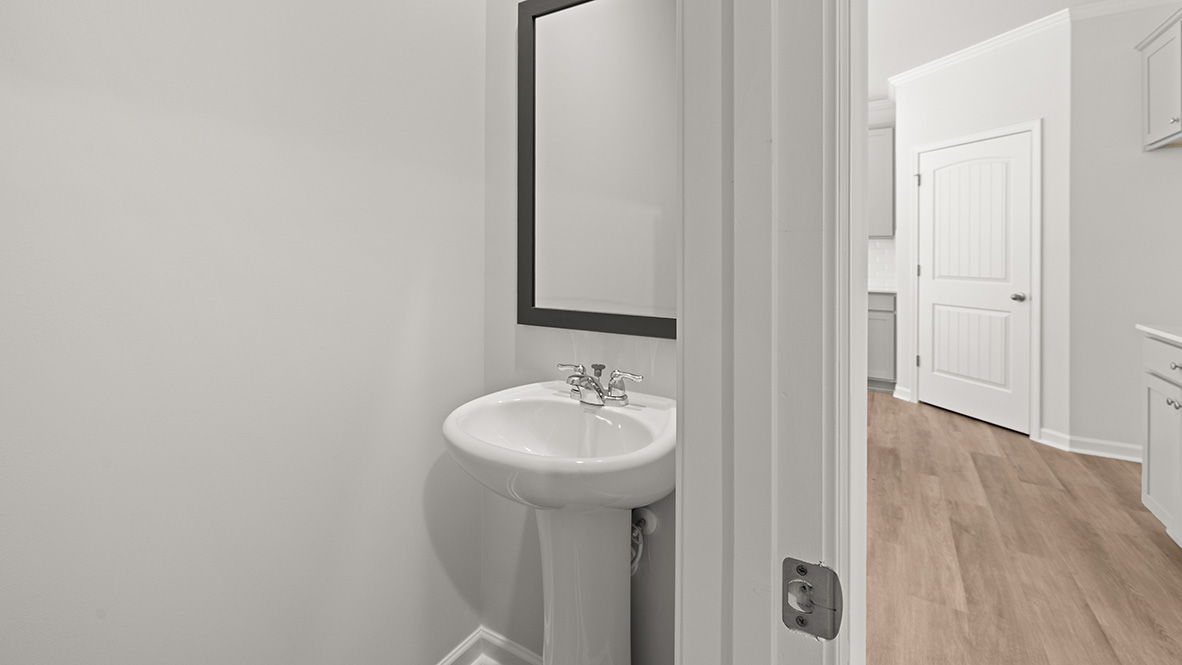 Half bath with a pedestal sink and a square mirror.