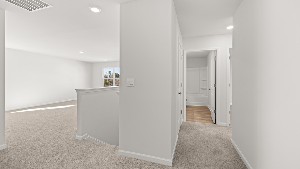 View from the hallway to the other bedrooms, a full bath, the stairwell, and the upstairs living area.