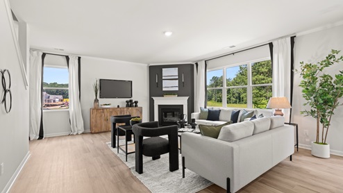 Spacious living room with brown flooring, white walls and windows