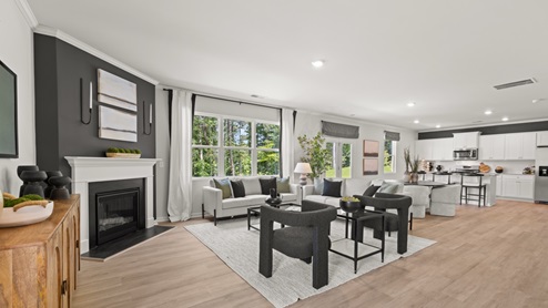 Spacious living room with brown flooring, white walls and windows