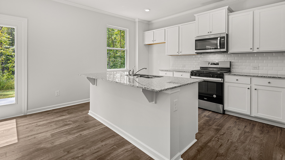 Open-concept kitchen with island sink, white shaker-style cabinets, stainless steel appliances, and a single kitchen window